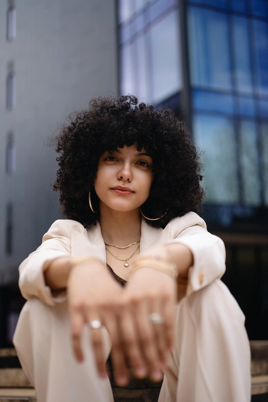 Picture of Sarah Mitchell sitting on the steps with arms on her knees, with a subtle smile.
